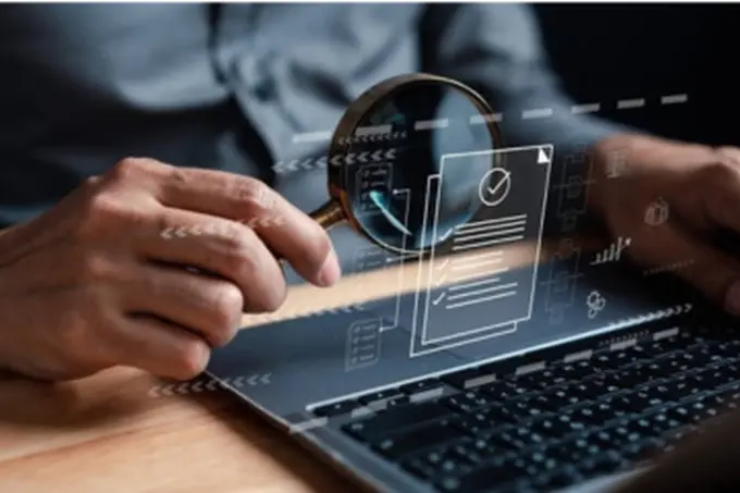 Magnifying glass over a digital checklist at a laptop, illustrating business discovery and digital research